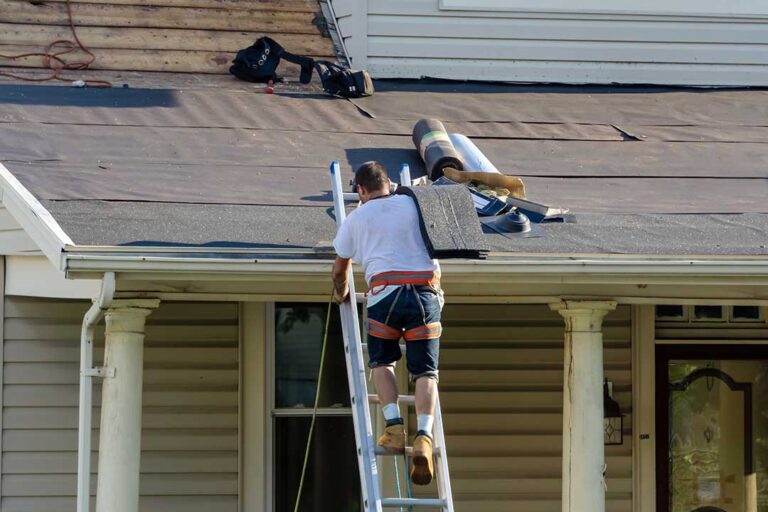 Homeowner checking roof gutters from the ground beside a seasonal residential house.