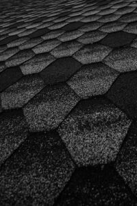 Homeowner examining labeled roof components beside shingles, flashing, and attic ventilation materials.