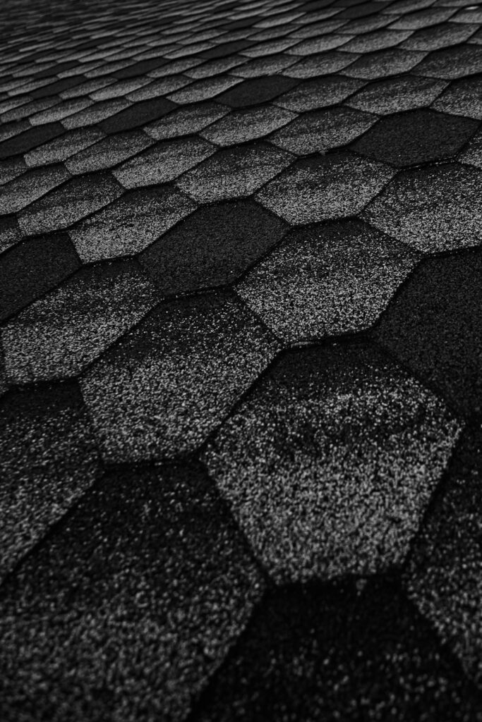 Homeowner examining labeled roof components beside shingles, flashing, and attic ventilation materials.